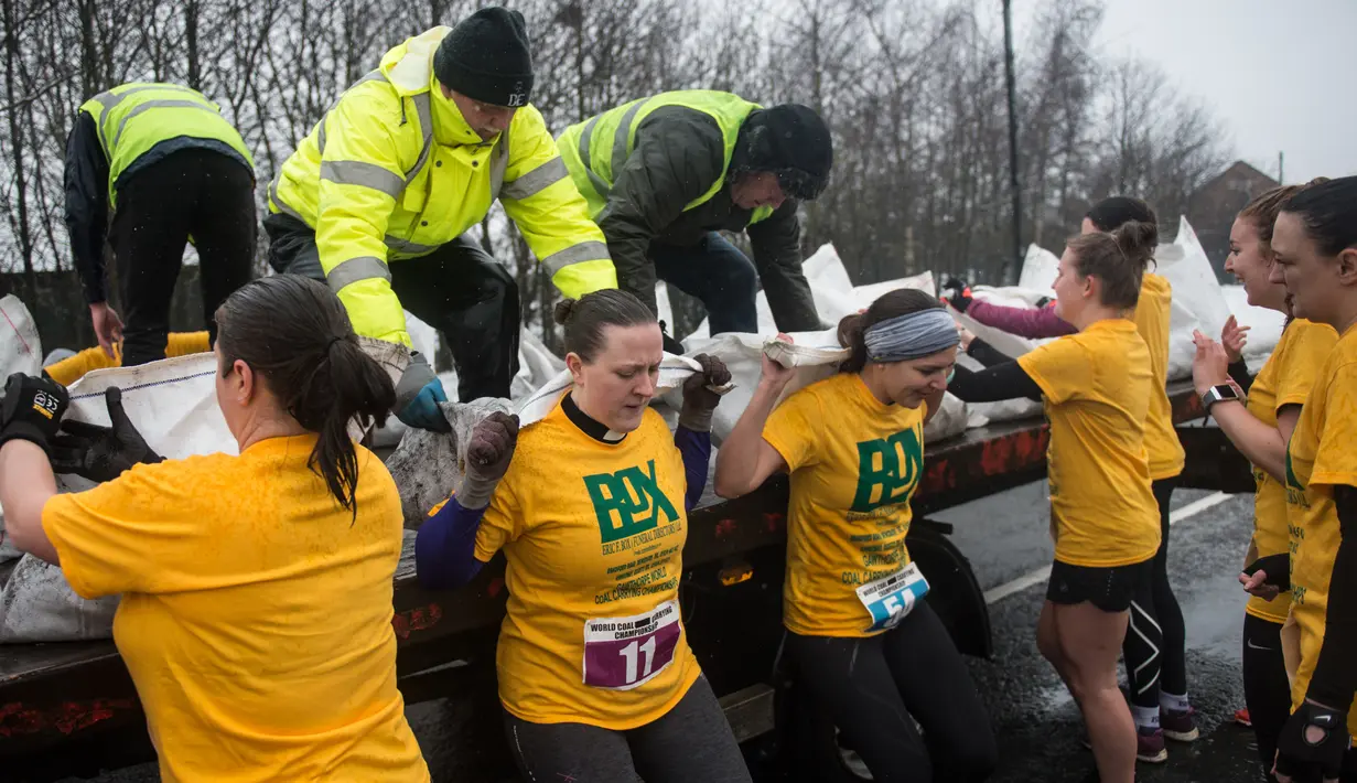 Para peserta bersiap mengambil karung berisi batu bara dalam World Coal Carrying Championships di Desa Gawthorpe, Wakefield, Inggris Utara, Senin (2/4). Kompetisi  tahunan mengakut karung batu bara ini sudah dilakukan sejak 1963. (OLI SCARFF/AFP)