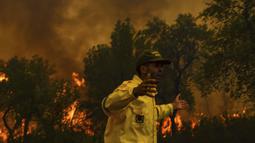 Seorang petugas pemadam kebakaran bereaksi ketika mencoba untuk memadamkan api yang disebabkan suhu ekstrem di Larache, Maroko utara, Jumat (15/7/2022). Petugas pemadam kebakaran dan militer berjuang untuk menahan beberapa kebakaran hutan di Maroko utara, ketika ratusan warga mengungsi dari rumah mereka karena kobaran api yang melanda petak besar hutan pinus. (AP Photo)