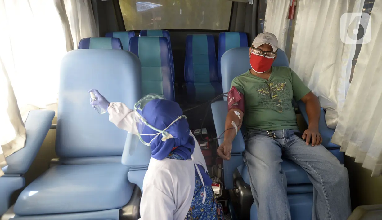 Petugas PMI menyemprotkan cairan saat mengambil darah pendonor di mobil donor darah keliling, Tangerang Selatan, Banten, Jumat (17/7/2020). PMI mengintensifkan pengoperasian mobil donor darah keliling untuk memenuhi persediaan stok darah saat pandemi COVID-19. (merdeka.com/Dwi Narwoko)