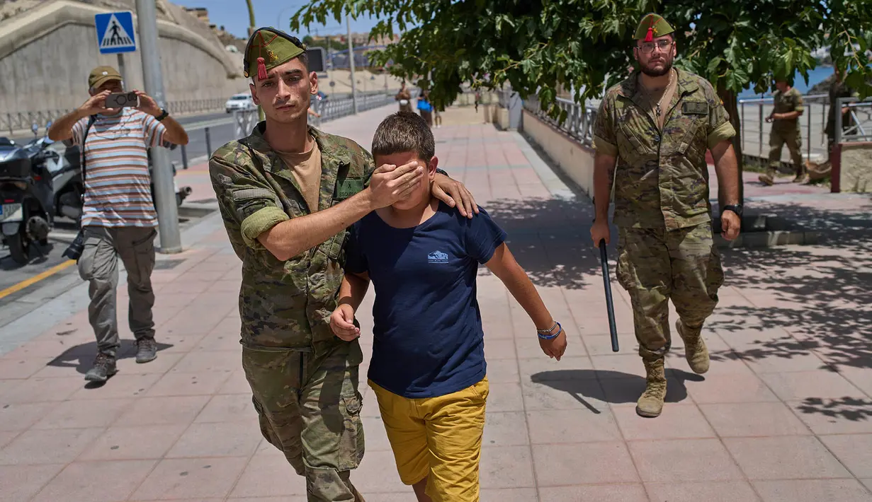 Seorang anak berusia 12 tahun yang menyeberang ke Spanyol tanpa pendamping menangis saat dikawal oleh seorang tentara Spanyol ke perbatasan Spanyol-Maroko dari wilayah kantong Spanyol di Ceuta, Senin, 3 Agustus 2026. (Foto AP/Bernat Armangue)