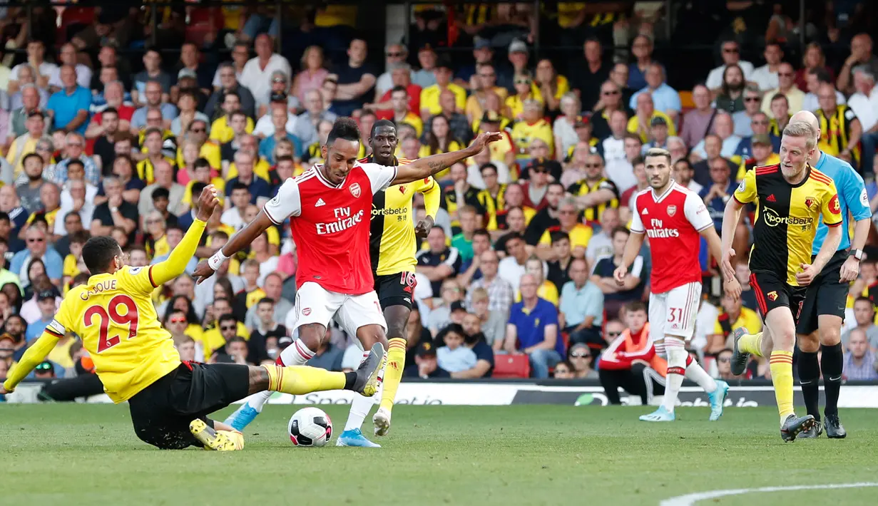 Striker Arsenal, Pierre-Emerick Aubameyang menembakkan bola ke arah gawang ketika pemain Watford, Etienne Capoue  berusaha untuk memblokir tendangannya pada pekan kelima Liga Inggris 2019-2020 di Vicarage Road, Minggu (15/9/2019). Arsenal ditahan imbang 2-2 Watford. (AP/Alastair Grant)