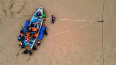 Foto menunjukkan pemandangan udara warga yang menyeberangi sungai dengan perahu setelah jembatan rusak akibat banjir di Juli, provinsi Aceh, pada Minggu 14 Desember 2025. Akses warga di kawasan Juli, Kabupaten Bireuen, Aceh, masih terputus setelah jembatan ambruk akibat banjir besar yang meluap dari Sungai Peusangan. (CHAIDEER MAHYUDDIN / AFP)