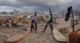 Warga Palestina, Khalil Abu Jayyab (kanan) dan Tahseen Abu Assi melakukan pemanasan sebelum berselancar di pantai Kota Gaza, Minggu, 28 Desember 2025. Pasca diberlakukannya gencatan senjata fase pertama yang didukung oleh Amerika Serikat mulai berlaku pada 10 Oktober 2025, warga Palestina mulai kembali ke Kota Gaza. (AP Photo/Jehad Alshrafi)