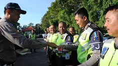 Petugas Polisi memberikan stiker bergambar bendera Indonesia dan Arab Saudi kepada rekannya selama persiapan menyambut kedatangan Raja Arab Saudi Salman bin Abdulaziz di Nusa Dua, Bali (2/3). (AFP Photo / Sonny Tumbelaka)