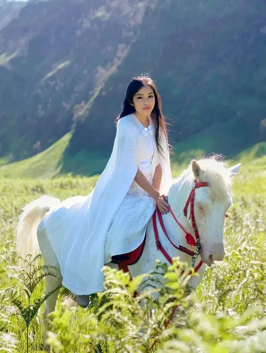Saat menaiki kuda putih, Tiffany tampil serba putih mengenakan outer cape panjang dipadukan inner putihnya. [@tiffanysoetanto]