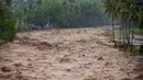 Data Pusat Pengendalian Operasi Penanggulangan Bencana (Pusdalops) BPBD Padang, Kecamatan Koto Tangah menjadi wilayah dengan jumlah terdampak terbesar, yaitu 20.983 warga. Tampak dalam foto, warga bertahan di tepi sungai saat banjir melanda Padang, Provinsi Sumatra Barat, pada Kamis 27 November 2025. (REZAN SOLEH/AFP)