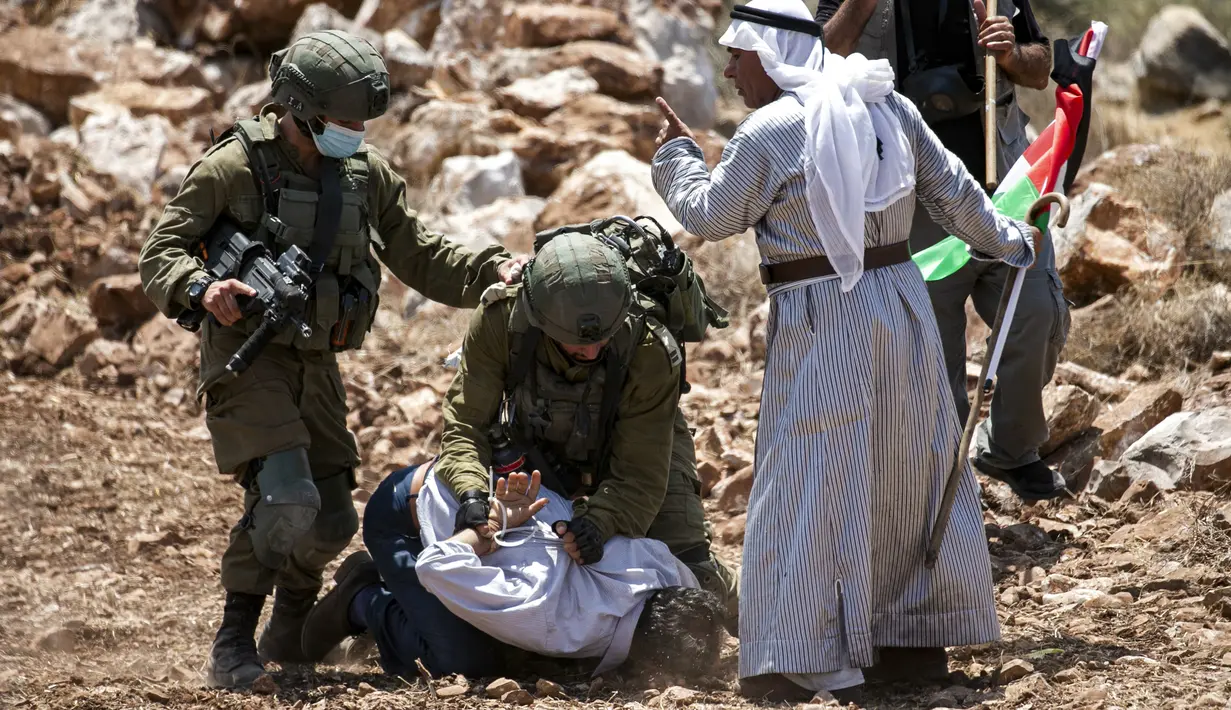 Unjuk Rasa Memprotes Pembukaan Lahan Israel: Tentara Israel membekuk pengunjuk rasa Palestina di dekat Desa Shoufah, Tepi Barat yang diduduki Israel (20/8/2020). Israel menangkap mereka yang menentang pembukaan lahan sebagai bagian dari proyek permukiman Israel di wilayahnya. (AFP/JAAFAR ASHTIYEH)