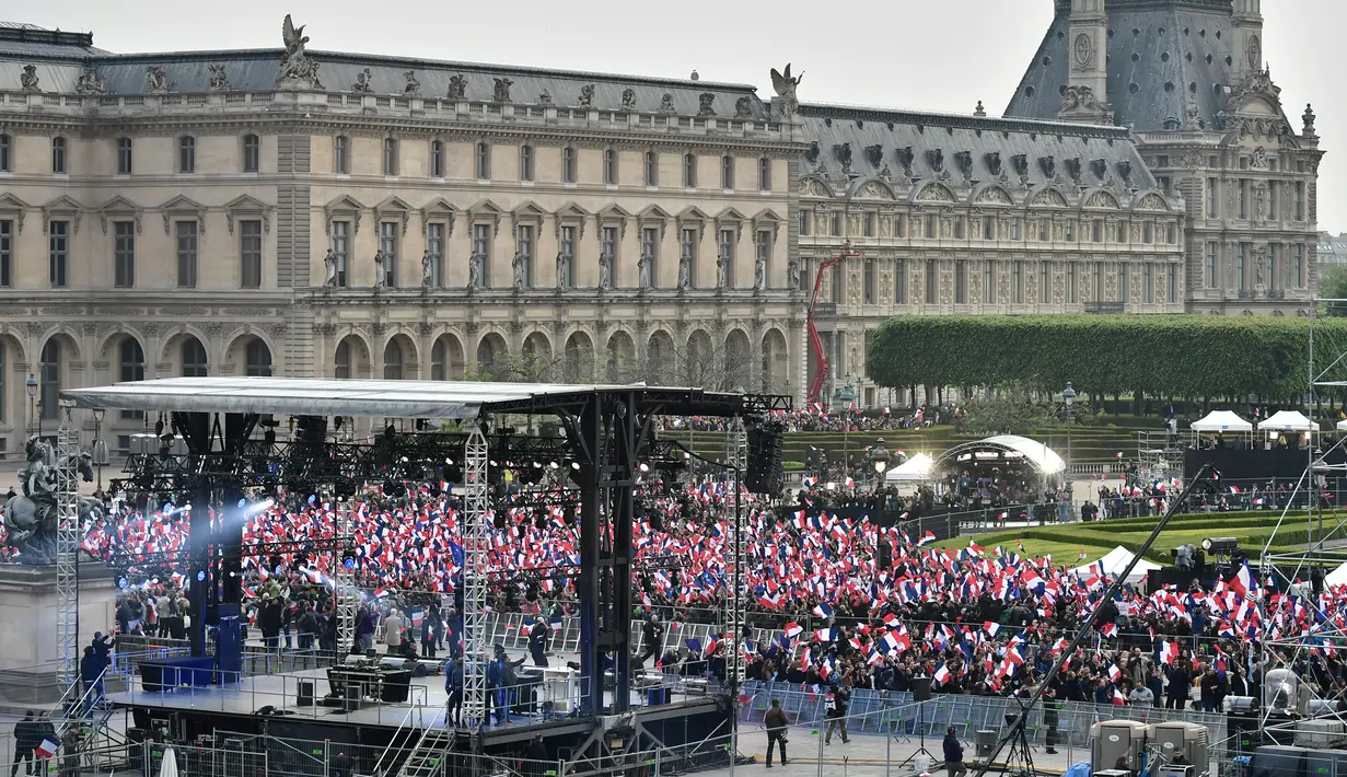 Ratusan pendukung Emmanuel Macron berkumpul di depan piramida kaca di taman museum Louvre, Paris, Minggu (7/5). Ratusan pendukung Emmanuel Macron menyambut kemenangan kandidat termuda yang terpilih sebagai presiden Prancis itu. (PHILIPPE LOPEZ/POOL/AFP)