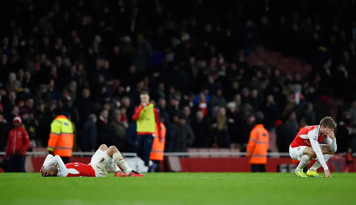 Gelandang Arsenal, Theo Walcott (kiri) dan Nacho Monreal terlihat sedih usai pertandingan melawan Swansea City pada lanjutan liga Inggris di Stadion Emirates (2/3). Swansea menang atas Arsenal dengan skor 2-1. (Reuters/Dylan Martinez)