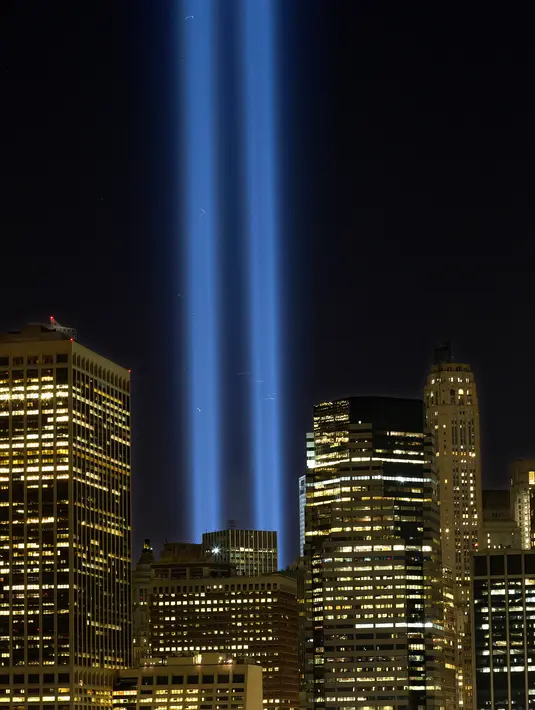 Sorotan cahaya kembar berwarna biru untuk peringati peristiwa serangan 9/11 di Kota New York, Minggu (10/9). Dua cahaya biru tegak lurus itu melambangkan menara kembar WTC yang menjadi sasaran serangan bunuh diri tersebut. (AP Photo/Mark Lennihan)