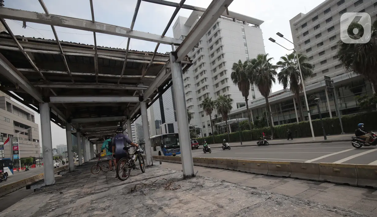 Sejumlah pesepeda melihat kerusakan Halte TransJakarta Bundaran HI, Jakarta, Jumat (9/10/2020). Demo menolak omnibus law Undang-Undang (UU) Cipta Kerja diwarnai kericuhan dan pembakaran terhadap sejumlah halte Transjakarta. (Liputan6.com/Angga Yuniar)