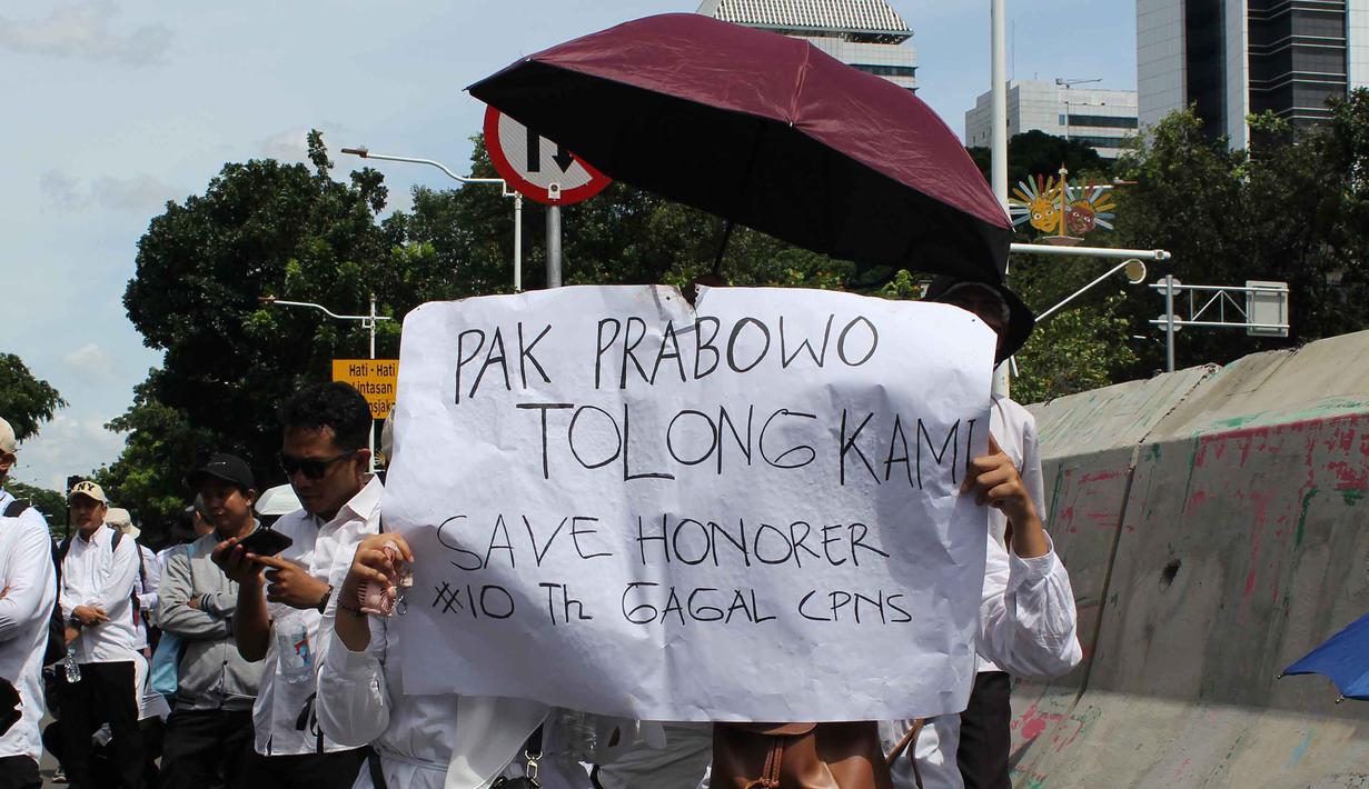 Para peserta aksi mendesak Presiden Prabowo Subianto, Kementerian PAN-RB, serta para kepala daerah untuk segera menerbitkan kebijakan afirmatif yang memberikan kepastian status, perlindungan hukum, dan peningkatan kesejahteraan bagi tenaga honorer non-database di seluruh Indonesia. Tampak dalam foto, massa dari Aliansi Honorer Non Database BKN Gagal Calon Pegawai Negeri Sipil (CPNS) Indonesia menggelar Aksi Damai Jilid 2 Nasional di kawasan Silang Selatan Monumen Nasional, Jakarta Pusat, pada Senin (17/11/2025). (merdeka.com/magang/Rendi Saputra)