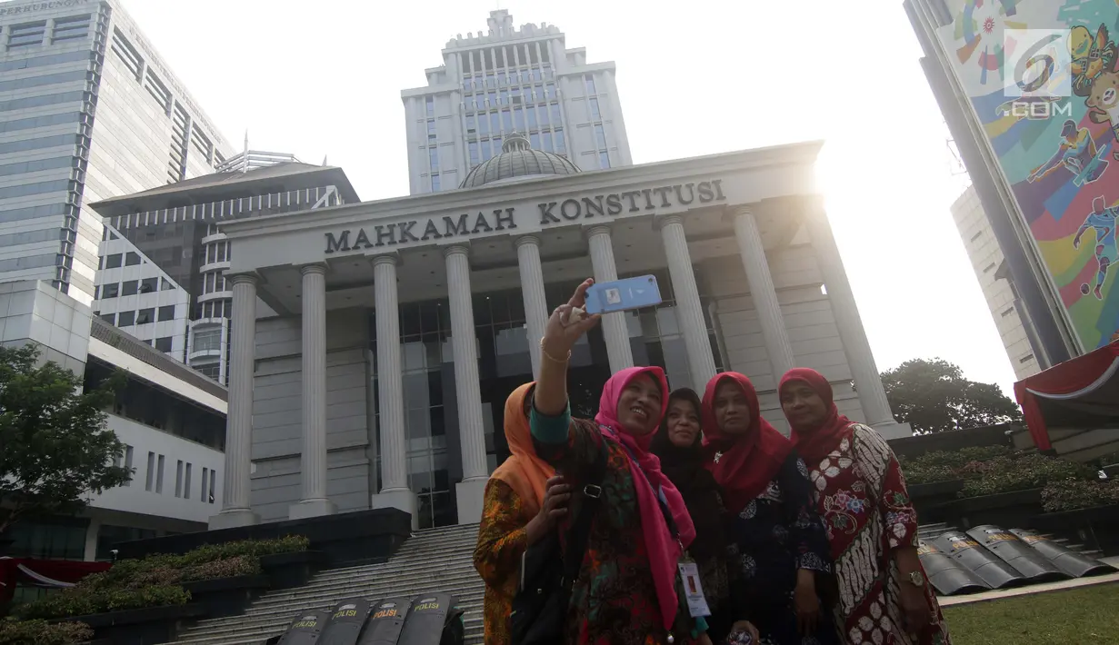 Warga berfoto di halaman depan Gedung Mahkamah Konstitusi, Jakarta, Kamis (13/6/2019). Mahkamah Konstitusi akan menggelar sidang Perselisihan Hasil Pemilihan Presiden/Wakil Presiden Pemilu 2019 pada, Jumat (14/6). (Liputan6.com/Helmi Fithriansyah)
