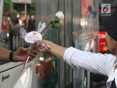 Relawan Jokowi saat membagikan bunga mawar di Kawasan Sarinah, Jakarta, Minggu (29/9/2019). Aksi bagi bunga tersebut merupakan aksi damai kami bersama Jokowi. (Liputan6.com/Angga Yuniar)