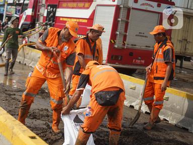 Petugas Penanganan Prasaran dan Sarana Umum (PPSU) membersihkan lumpur yang mengendap di sepanjang Jalan Jatinegara Barat, Kampung Melayu, Jakarta Timur, Kamis (2/1/2020). Petugas melakukan bersih-bersih menyusul mulai surutnya banjir di kawasan tersebut. (Liputan6.com/Immanuel Antonius)