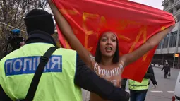 Petugas menghalau aktivis wanita gerakan hak perempuan Femen saat unjuk rasa memperingati 100 tahun Revolusi Bolshevik di pusat kota Kiev, Ukraina (7/11). (AFP Photo/Genya Savilov)