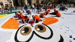 Sejumlah relawan membuat mosaik raksasa dari 100 ton limbah tutup botol di kota Novi Sad, Serbia, Sabtu (30/9). Hampir 800.000 tutup botol dibutuhkan dalam proyek meningkatkan bantuan bagi anak-anak penyandang cacat tersebut. (AP/Darko Vojinovic)