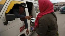 Seorang warga menerima masker yang dibagikan para relawan di kawasan Berastagi, Karo, Sumatera Utara, 25 Juni 2015. Debu vulkanik akibat erupsi Gunung Sinabung masih menutupi sebagian Kota Berastagi. (REUTERS/Beawiharta)