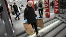 Seorang perempuan membawa dua kantong belanja meninggalkan toko H&M pada hari terakhir pembukaan di Moskow, Rusia, Rabu (30/11/2022). H&M menutup seluruh tokonya sebagai bentuk protes atas serangan Rusia ke Ukraina.  (AP Photo/Alexander Zemlianichenko)