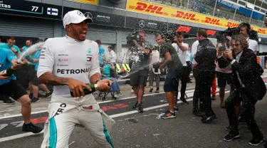 Pembalap Mercedes, Lewis Hamilton menyemprotkan sampanye saat merayakan keberhasilannya memenangkan GP Italia di Sirkuit Monza di Monza, Italia, (2/9). Saat ini Hamilton menempati urutan pertama klasemen dengan 231 poin. (AP Photo/Antonio Calanni)