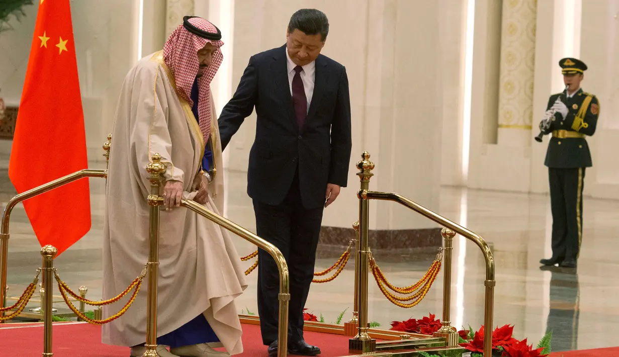  Presiden China Xi Jinping membantu Raja Arab Saudi Salman bin Abdulaziz al-Saud berjalan saat mengikuti upacara penyambutan di Beijing, China (16/3). (AP Photo / Ng Han Guan)