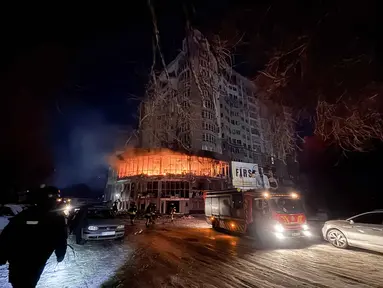 Petugas pemadam kebakaran berdiri di dekat bangunan tempat tinggal yang terbakar setelah serangan pesawat tak berawak Rusia di Zaporizhzhia pada 2 Januari 2026, di tengah invasi Rusia ke Ukraina. Rusia melancarkan serangan udaranya ke wilayah Zaporizhzhia, Ukraina. (Darya NAZAROVA/AFP)
