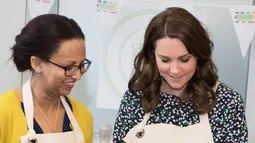 Kate Middleton bersama rekannya mempersiapkan masakan untuk acara Commonwealth Big Lunch di Luke's Community Centre, London, Inggris (22/3). Big Lunch merupakan acara tahunan terbesar di Inggris. (Paul Edwards/ Pool via AP)