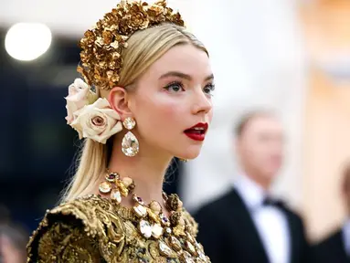 Anya Taylor-Joy sukses bikin publik terkesima saat hadiri Met Gala 2018 lalu. Ia tampil memesona dengan gaun Dolce & Gabbana berhias renda emas dengan hiasan kepala penuh bunga. (Liputan6.com/IG/@anyataylorjoy)