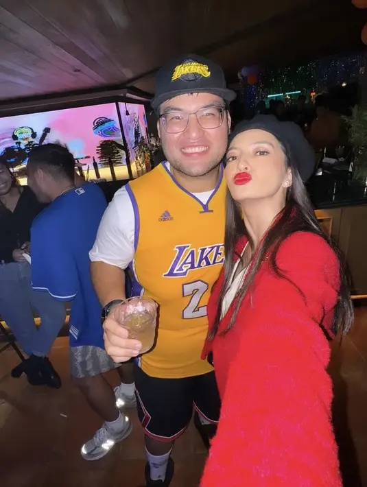 Raline Shah tampil dengan baju merah serasi dengan lipstiknya, ia pun bersama sang adik Rollan Shah yang mengenakan jersey basket Lakersnya. [@ralineshah]