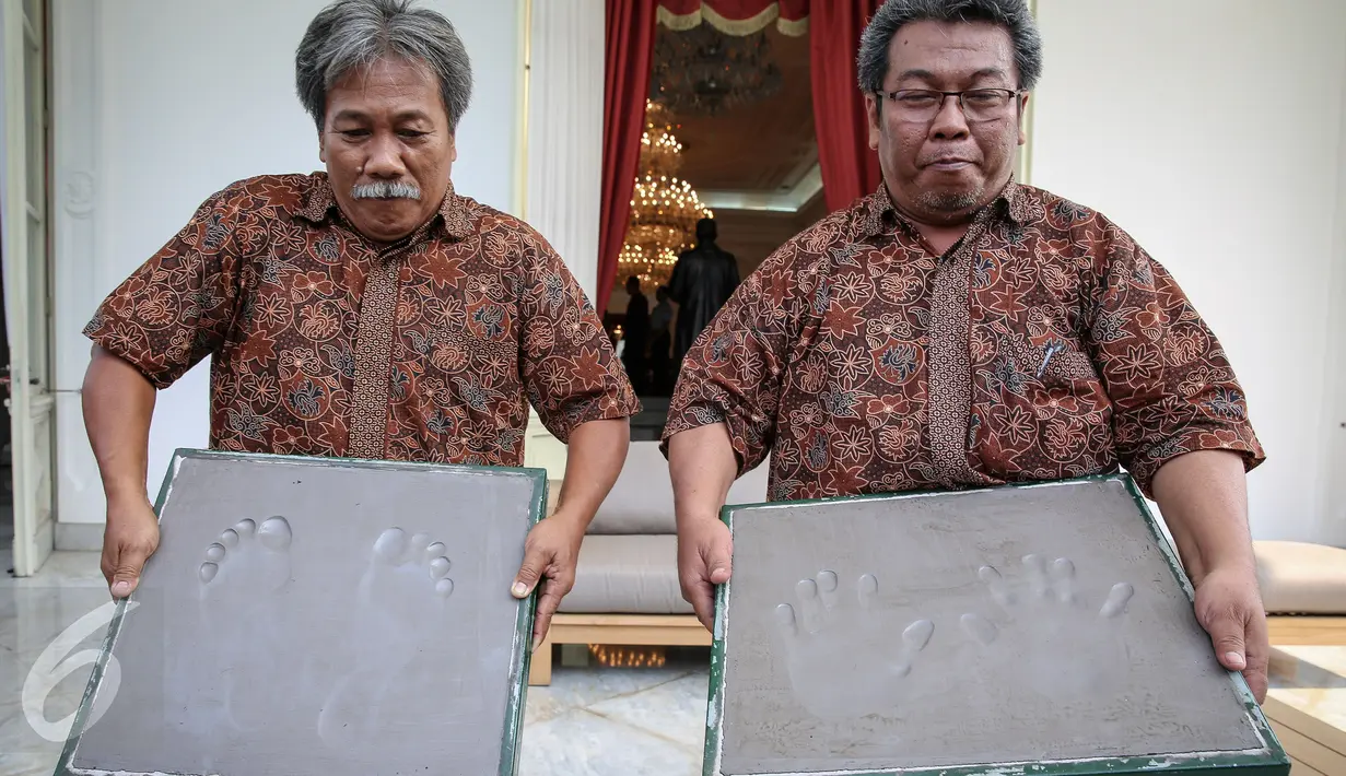 Pematung Amboro Liring (kanan) bersama rekannya menunjukkan bekas injakan kaki dan tangan Presiden Joko Widodo di Istana Merdeka, Jakarta, Selasa (13/10/2015). Cetakan tersebut akan diletakkan di Taman Pintar Yogyakarta. (Liputan6.com/Faizal Fanani)