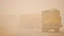 <p>Sejumlah truk melaju melalui badai pasir Musim Semi di kota Nasiriyah, di provinsi Dhi Qar, Irak selatan (5/5/2022). Irak dihantam oleh serangkaian badai semacam itu pada bulan April, menghentikan penerbangan dan membuat puluhan orang dirawat di rumah sakit karena masalah pernapasan. (AFP/Asaad Niazi)</p>