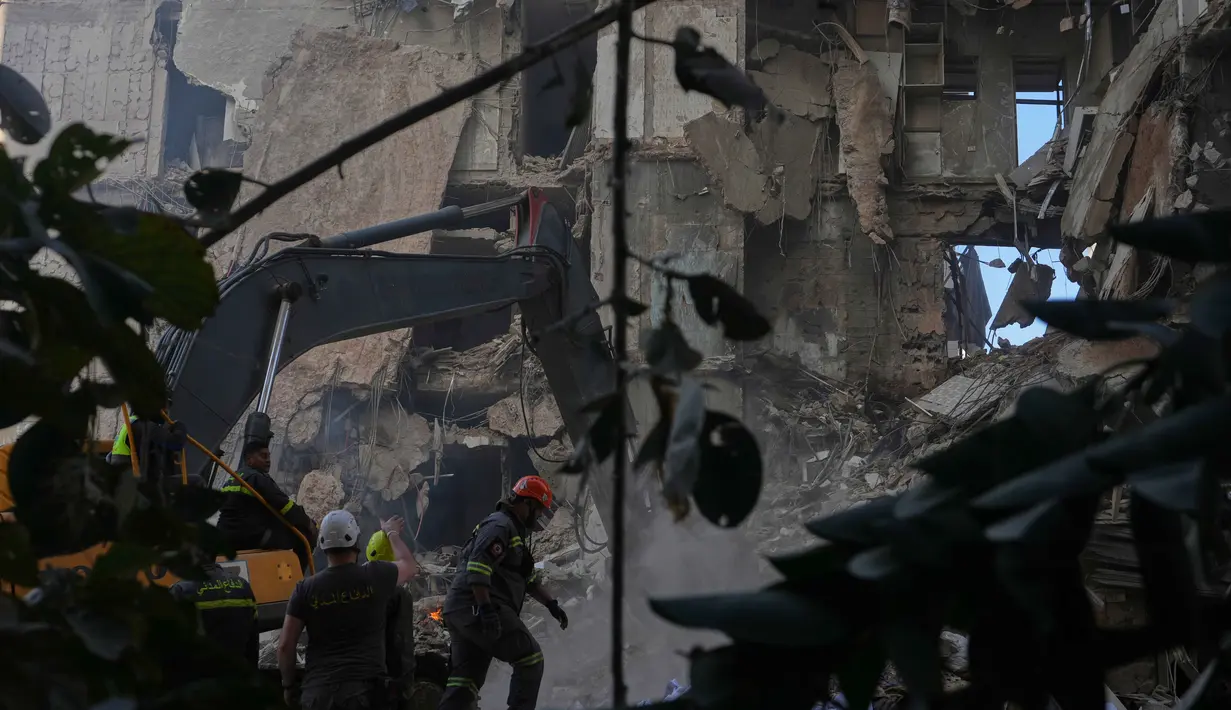 Dengan menggunakan 50 jet tempur, serangan Israel menghantam 100 target dalam waktu hanya 10 menit. Tampak dalam foto, para pekerja pertahanan sipil Lebanon dan sebuah ekskavator membersihkan puing-puing di lokasi bangunan yang hancur akibat serangan udara Israel sehari sebelumnya di pusat kota Beirut, Lebanon, Kamis 9 April 2026. (AP Photo/Hassan Ammar)