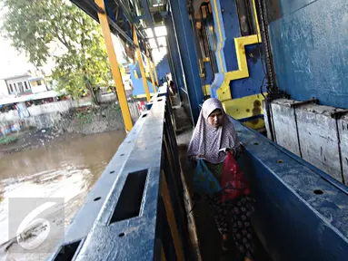 Warga melintasi jalan setapak di pintu air Petamburan, Jakarta, Jumat (17/2). Warga terpaksa melewati pintu air karena tidak ada jembatan penyeberangan orang di kawasan tersebut. (Liputan6.com/Immanuel Antonius)