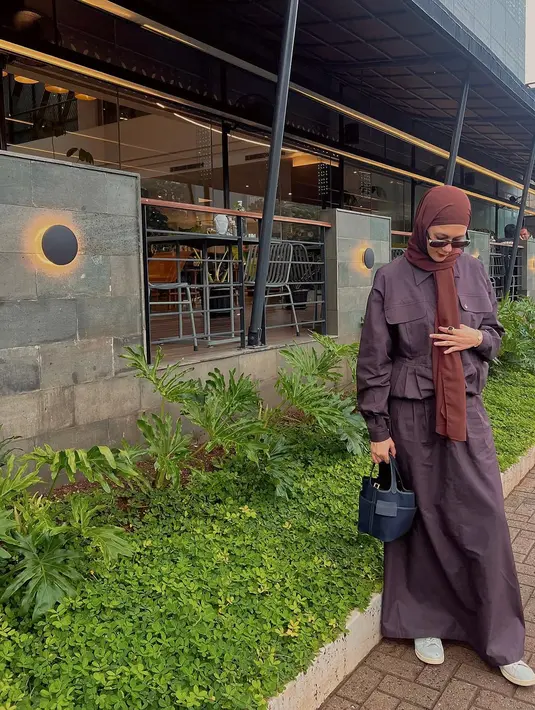 Paduan kemeja berkantung dan rok panjang keunguan bikin Paula tampil stylish. Ditambah dengan kerudung lilit cokelat, sneakers putih, dan kacamata hitam [@paula_verhoeven]