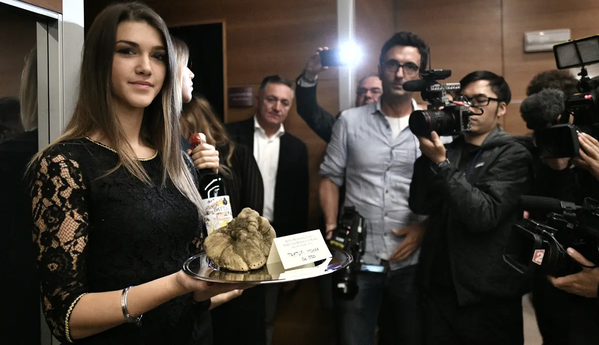 Seorang wanita menampilkan jamur truffle putih langka seberat 850 gram selama lelang World White Truffle ke-19 di Alba, Italia, 11 November 2018. Kota Alba sudah menyelenggarakan lelang jamur truffle putih langka selama 88 tahun. (Marco BERTORELLO/AFP)