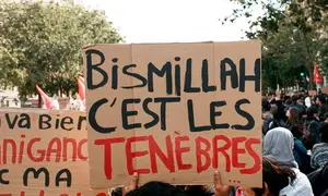 Seorang demonstran mengangkat papan bertuliskan "Bismillah, C’est Les Ténèbres" selama demonstrasi oleh siswa sekolah menengah di Place de la Bastille di Paris pada 8 Oktober 2026, sebagai bagian dari protes nasional terhadap kondisi pembelajaran. (ADNAN FARZAT / NURPHOTO VIA AFP)