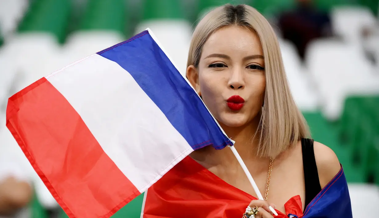 Fans Prancis berpose dengan memegang bendera saat menyaksikan laga Prancis melawan Tunisia pada laga Piala Dunia 2022 di Stadion Education City, Rabu (14/11/2022). (AFP/Franck Fife)