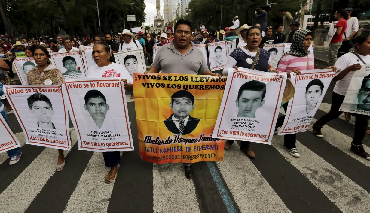 Sejumlah kerabat memegang poster bergambar 43 mahasiswa yang hilang dalam protes di Meksiko, (26/8/2015). Para mahasiswa menghilang sejak 26 September 2014 di kota barat daya Iguala. (REUTERS/Henry Romero)