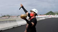 Seorang pawang hujan melakukan ritual saat sesi latihan bebas MotoGP Indonesia di Sirkuit Mandalika, Mandalika, Lombok Tengah, Nusa Tenggara Barat, Jumat (18/3/2022). (AFP/Bay Ismoyo)