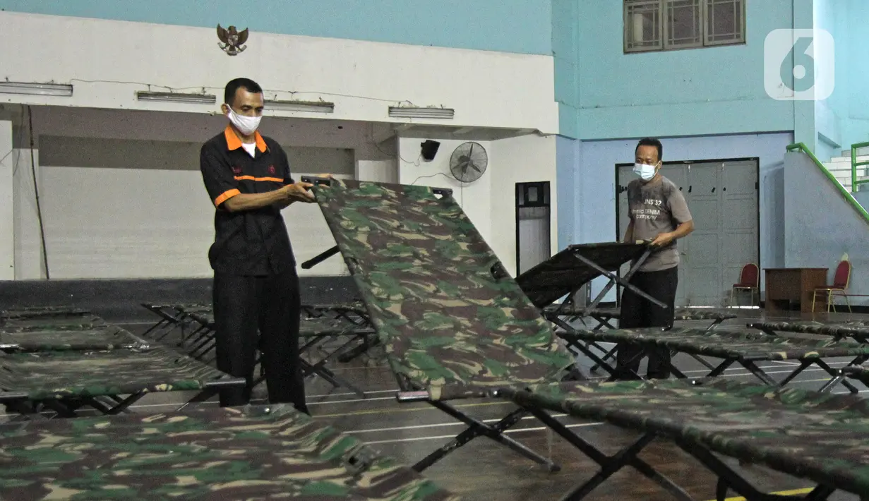 Petugas menyiapkan tempat singgah sementara bagi warga yang baru kembali ke Jakarta di GOR Cipayung, Jakarta, Selasa (18/5/2021). GOR ini jadi tempat singgah bagi mereka yang tidak memiliki tempat layak untuk isolasi mandiri sambil menunggu hasil tes swab antigen/PCR. (Liputan6.com/Herman Zakharia)