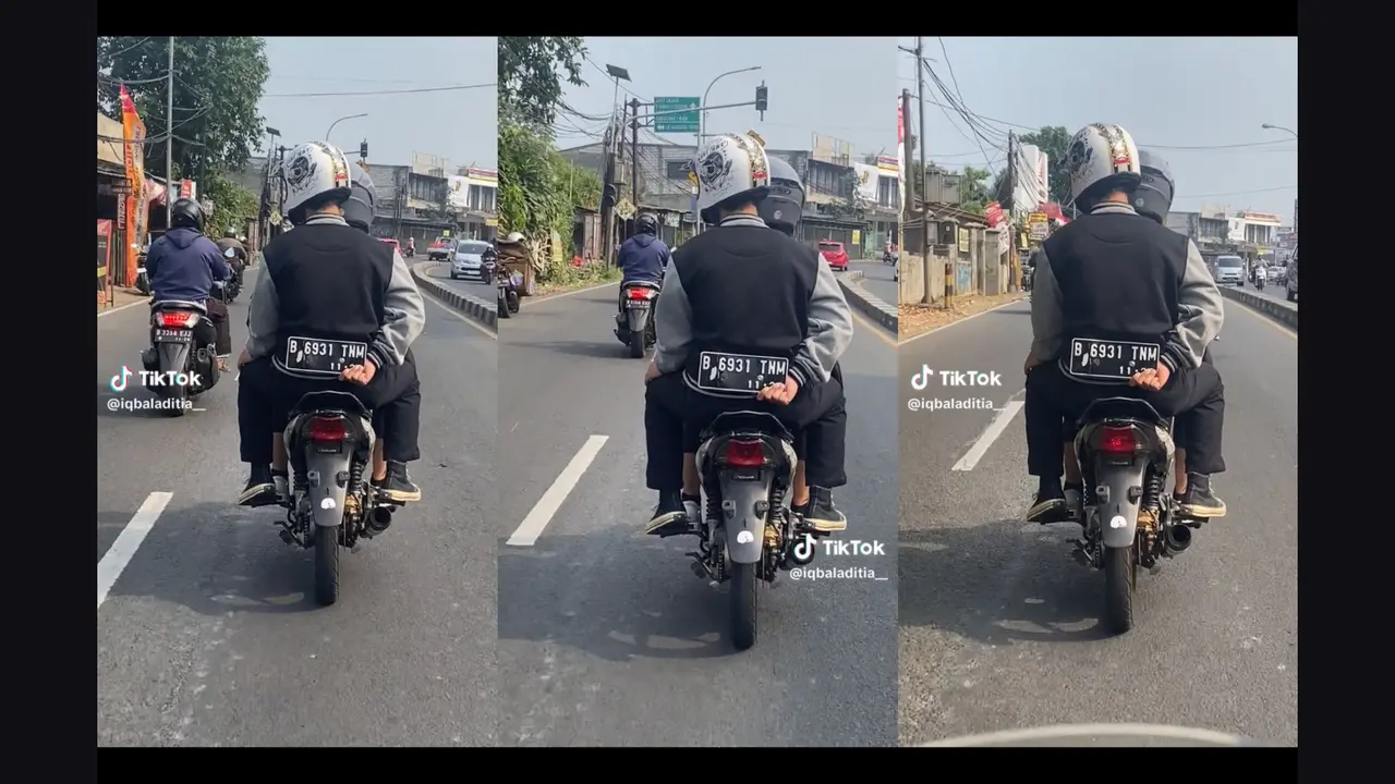 Penumpang Memegang Plat Motor di Belakang Punggungnya