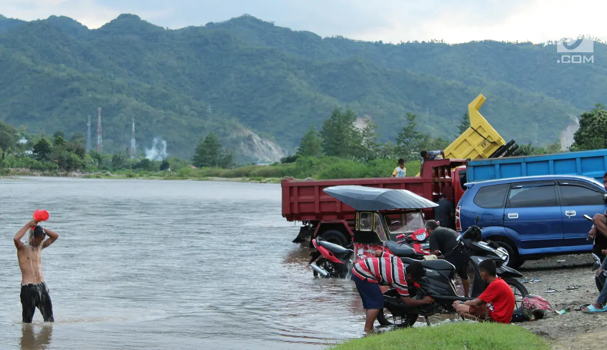 Sejumlah orang mencuci kendaraannya sementara warga lainnya mandi di sungai Bone, kompleks Jembatan Talumolo II, Kelurahan Talumolo, Gorontalo, Senin (19/11). Tempat itu menjadi kawasan pencucian kendaraan yang gratis.  (Liputan6.com/Arfandi Ibrahim)