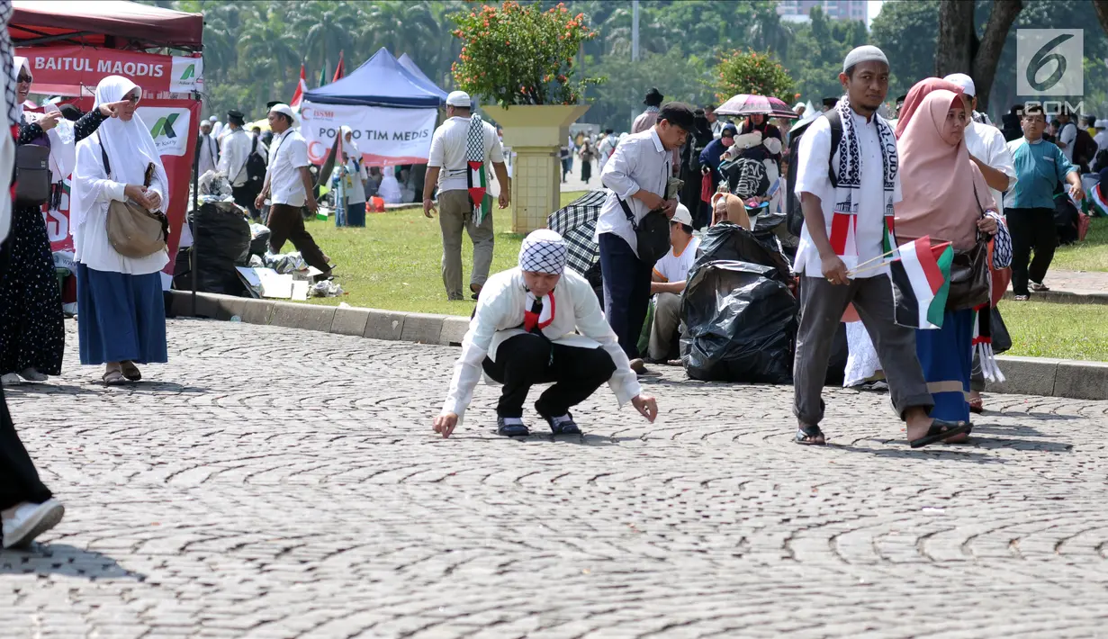 Peserta aksi memunguti ceceran sampah di halaman Monumen Nasional usai aksi, Jakarta, Jumat (11/5). Ribuan massa melakukan aksi menyoroti konflik Palestina dan Israel pada perebutan bangunan suci atau Baitul Maqdis. (Liputan6.com/Helmi Fithriansyah)