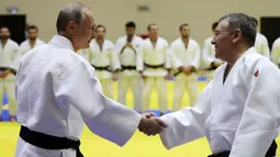 Presiden Rusia, Vladimir Putin menyapa pelatih sebelum mengikuti latihan judo bersama atlet nasional Rusia di Sochi, Kamis (14/2). Judo merupakan salah satu olahraga kegemaran Putin yang telah digeluti sejak masa muda. (Mikhail KLIMENTYEV/SPUTNIK/AFP)