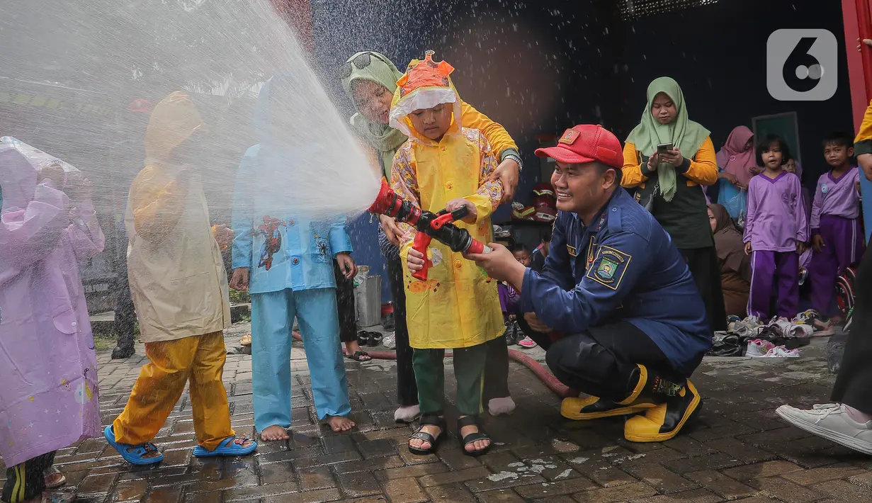 Petugas pemadam kebakaran (Damkar) Kota Tangerang membantu siswa Taman Kanak-Kanak (TK) menyemprotkan air untuk memadamkan api saat edukasi pengenalan profesi Damkar di Kota Tangerang, Banten (22/11/2023). (Liputan6.com/Angga Yuniar)