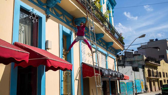 Seorang pria mengecat bagian balkon di Havana, Kuba (28/12). Kota ini terletak sekitar 144 kilometer di selatan-barat daya dari Key West, Florida. (AP Photo / Desmond Boylan)