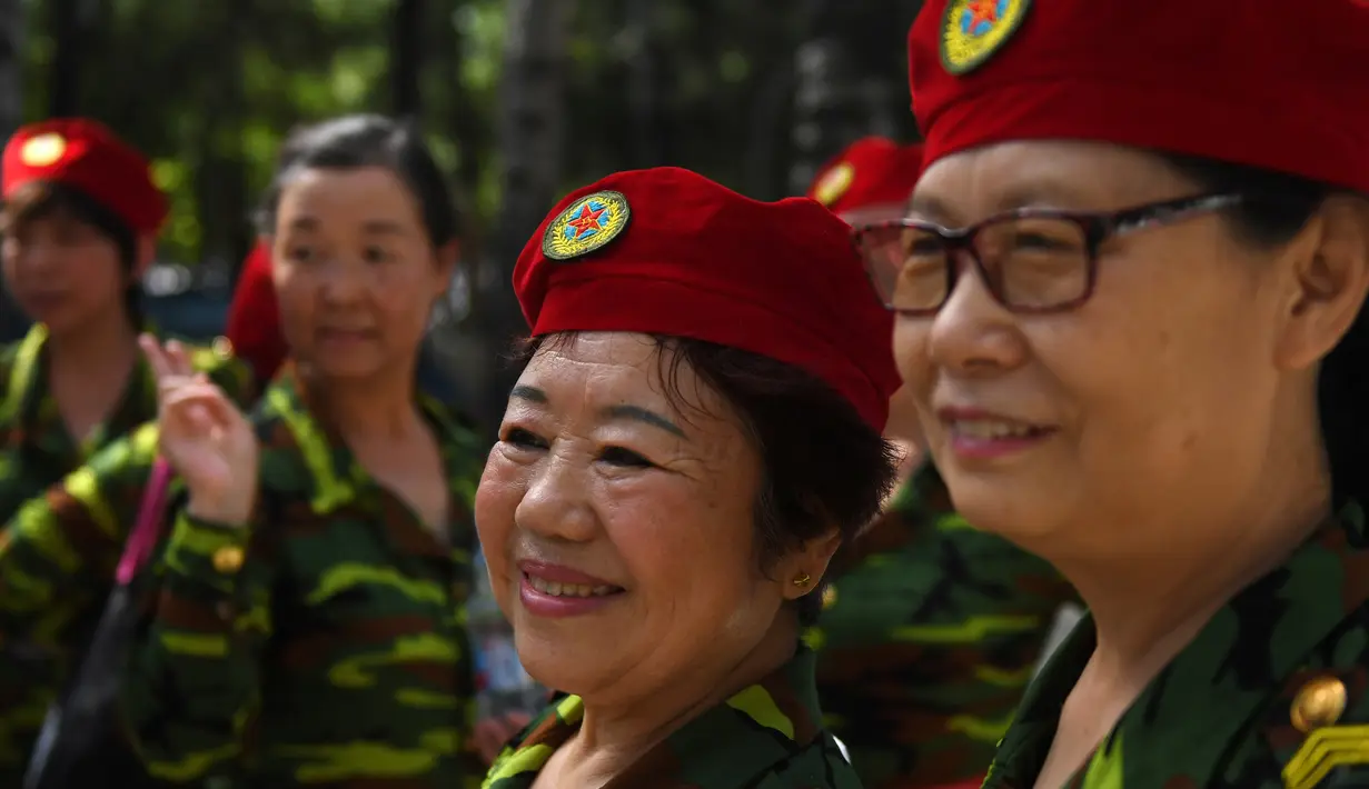 Sejumlah wanita lansia tampil mengenakan pakaian bergaya militer berfoto bersama usai mengikuti Hari Kebugaran Nasional di Beijing, Tiongkok (8/8). (AFP Photo/Greg Baker)