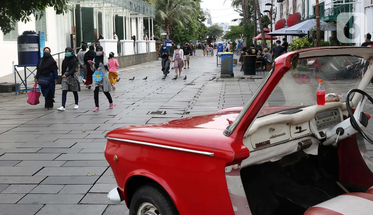 Pengunjung menggunakan masker berjalan-jalan di kawasan Kota Tua Jakarta, Kamis (29/10/2020). Libur panjang di masa pemberlakuan PSBB transisi Jakarta dimanfaatkan warga untuk mengunjungi lokasi-lokasi wiisata. (Liputan6.com/Helmi Fithriansyah)
