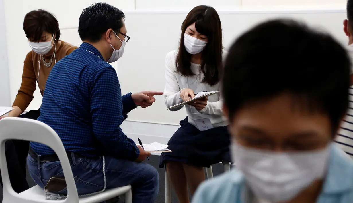 Seorang peserta pria berbincang dengan peserta wanita menggunakan masker dalam acara layanan kencan di Tokyo, Jepang, (16/10). Penggunaan masker ini untuk menghindari penyebaran penyakit saat layanan kencan singkat. (REUTERS/Kim Kyung-Hoon)