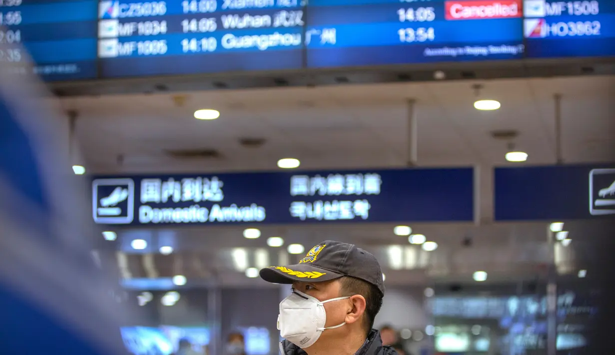 Pelancong berdiri di bawah papan informasi yang menunjukkan penerbangan dari Wuhan telah dibatalkan di Bandara Internasional Ibu Kota Beijing pada Kamis (23/1/2020). China menangguhkan semua transportasi dari dan ke kota Wuhan, yang merupakan pusat penyebaran virus korona. (AP/Mark Schiefelbein)
